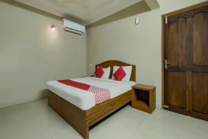 a bedroom with a bed with red pillows and a wooden door at Collection O Kadavanthra Near South Railway Station in Cochin