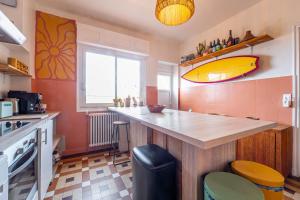 a kitchen with a counter with a surfboard on the wall at La Boga Surf House Biscarrosse Plage in Biscarrosse +2 photos