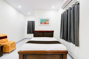 a bedroom with a bed and a chair at Super Collection O Vanasthalipuram in Hyderabad +32 photos