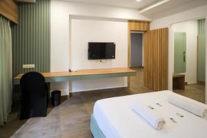 a room with a bed and a desk with a tv at Hotel Heraa Boarding Lodging in Mangalore