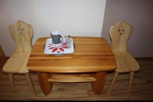 a wooden table with two chairs and a tea set on it at Noclegi KLARA in Zawoja