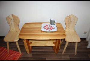 a wooden table with two chairs and a mug on it at Noclegi KLARA in Zawoja