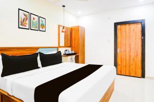 a bedroom with a large bed and a wooden door at Super Townhouse Rajahmundry in Rājahmundry