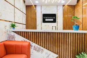 a waiting room with an orange chair and a counter at Super Townhouse Rajahmundry in Rājahmundry