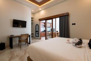 a bedroom with a bed and a desk and a television at Villa Sakura ll seminyak in Seminyak