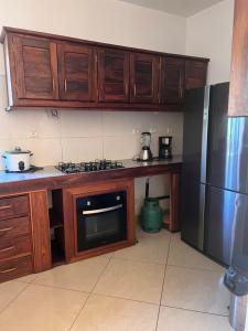 a kitchen with wooden cabinets and a stainless steel refrigerator at Appartement OASIS in Hell-Ville +2 photos