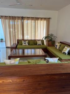 a living room with a green couch and tables at Appartement OASIS in Hell-Ville