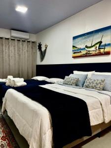 a bedroom with two beds and a painting on the wall at Pousada Águas da Grota - Penha - SC in Penha