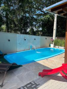 a swimming pool with a faucet and a red chair at Pousada Águas da Grota - Penha - SC in Penha
