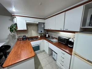 a kitchen with white cabinets and a wooden counter top at Departamento Full Equipado in Concón