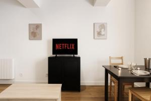 a television sitting on top of a black stand in a room at Le Nid Mâconnais Central - Gare - Calme in Mâcon +1 photo