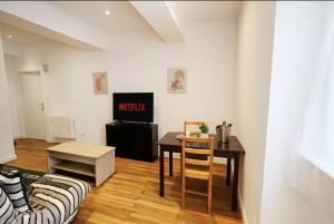 a living room with a table and a tv at Le Nid Mâconnais Central - Gare - Calme in Mâcon
