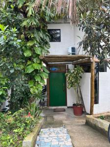 uma porta verde numa casa com árvores em Quarto com banho privado e lavanderia em Florianópolis