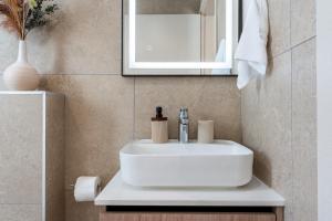 a bathroom with a white sink and a mirror at Densho 2-Bedroom Luxury Apartment in Larnaka +11 photos