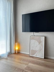 a flat screen tv on a wall with a painting at VJ House in Fukuoka