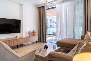a living room with a television and a couch and chairs at Densho 2-Bedroom Luxury Apartment in Larnaka