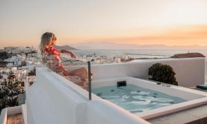 a woman sitting on a ledge with a hot tub at HIGH END Unique 270 degree aerial sea view suite in Naxos Chora