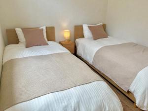 two beds in a bedroom with a lamp on a night stand at VJ House in Fukuoka