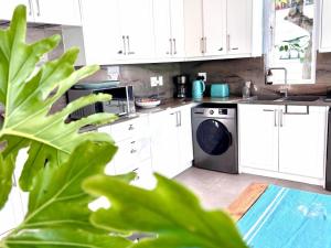 a kitchen with white cabinets and a washing machine at Starry Starry Night - Cape Town, 3-Bedroom 3-Bathroom Seaside House in Three Anchor Bay in Cape Town