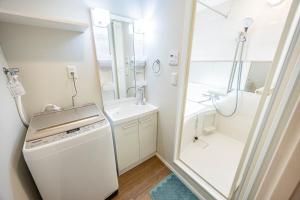 Un baño blanco con ducha y lavabo. en Hiro Yanaka hotel, en Tokio 27 fotos más