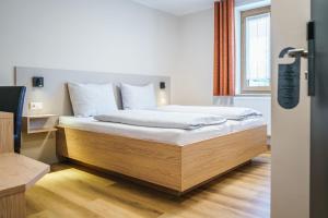 a bedroom with a bed with white sheets and a window at Gasthof Geier in Wörth an der Donau