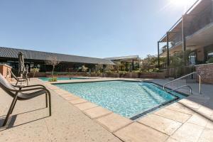 una piscina con una sedia accanto a un edificio di Cityescapes 2F in Waterfall Midrand - Beautiful self catering 2 bedroom unit next to Kyalami Racetrack with free WiFi swimming pool gym and restaurant - Perfect for a small family a Midrand