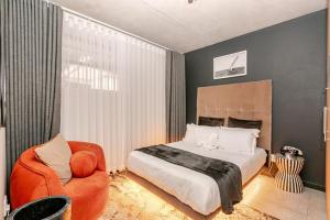 una camera da letto con un letto e una sedia di Cityescapes 2F in Waterfall Midrand - Beautiful self catering 2 bedroom unit next to Kyalami Racetrack with free WiFi swimming pool gym and restaurant - Perfect for a small family a Midrand Altre 100 foto