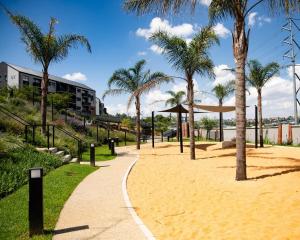 un vialetto con palme e una spiaggia di Cityescapes 2F in Waterfall Midrand - Beautiful self catering 2 bedroom unit next to Kyalami Racetrack with free WiFi swimming pool gym and restaurant - Perfect for a small family a Midrand