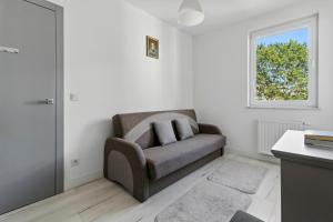 a living room with a chair and a window at Pełczyńskiego Comfort Stay by Solarento in Warsaw +12 photos