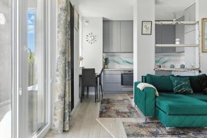 a living room with a green couch and a kitchen at Pełczyńskiego Comfort Stay by Solarento in Warsaw