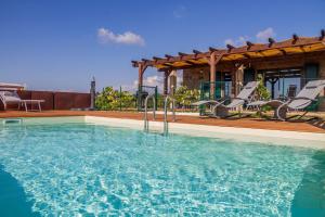 a swimming pool with chairs and a house at Agriturismo Ornelleta in Scansano