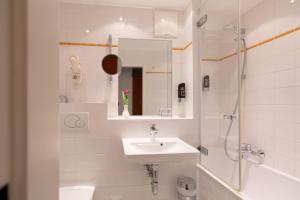 a white bathroom with a sink and a shower at Garner Hotel Vienna - Prinz Eugen by IHG in Vienna +35 photos
