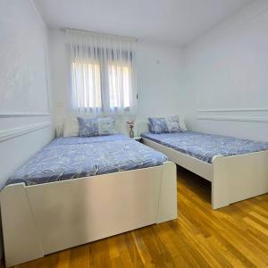 two beds in a room with white walls and wood floors at Apartment Nemanja by Princess Milena in Čučići +12 photos