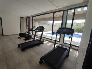 un gimnasio con 3 cintas de correr y una piscina en Coquet appartement avec piscine à 10min de l'aéroport Tunis - family only, en La Soukra