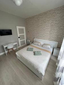 a bedroom with a white bed with a brick wall at La maison des Ducs, terrasse, BBQ, Proche centre in Nevers