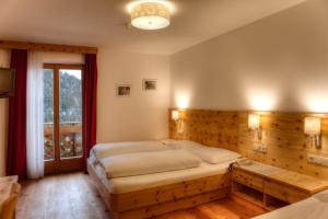 a bedroom with a large bed with a wooden wall at Pension Panorama in Monguelfo +20 photos