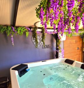 a bath tub with purple flowers hanging from a ceiling at Chalet Ponte Paradiso Suite & SPA in Santa Cristina Gela