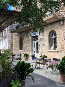 un bâtiment avec des tables et des chaises devant lui dans l'établissement La Petite Bastide-Central Apartment in Neffies, à Néffiès