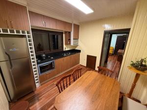 a kitchen with a wooden table and a refrigerator at Sua Casa no Centro Gramado, 1km Rua Coberta in Gramado