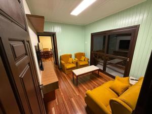 a living room with a yellow couch and two chairs at Sua Casa no Centro Gramado, 1km Rua Coberta in Gramado