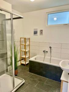 a bathroom with a bath tub and a sink at discovAIXR - Super Zentral mit Parkplatz, Küche, Netflix und mehr in Eisenach