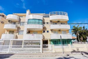 ein hohes Gebäude mit einem weißen Zaun davor in der Unterkunft 791 - Cobertura com piscina. 200m da PRAIA. BOMBINHAS - CENTRO in Bombinhas