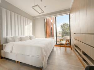 普卡尔帕Alma Residence的卧室里有一张白色的床和一扇大窗户