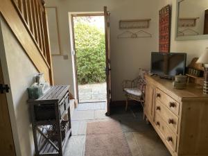 a living room with a television on a dresser and a door at The Shed in Stratford-upon-Avon