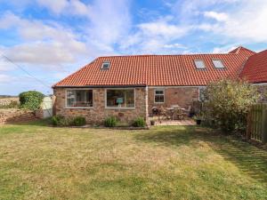 a brick house with a red roof on a yard at Barleycorn Cottage in Belford