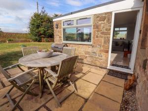 a table and chairs on a patio with a caravan at Barleycorn Cottage in Belford