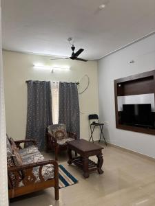 a living room with furniture and a flat screen tv at Sihi 2BHK in Mysore