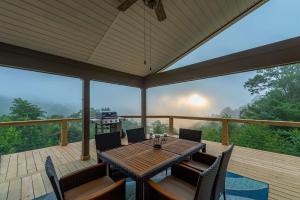 a patio with a table and chairs on a deck at Stunning Mtn Views Hot Tub Fire Pit Sleeps 8 in Waynesville
