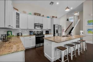 a kitchen with white cabinets and a kitchen island with bar stools at Sunset & Sand townhouse in Anna Maria Island