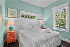 a bedroom with a white bed and two windows at Sunset & Sand townhouse in Anna Maria Island